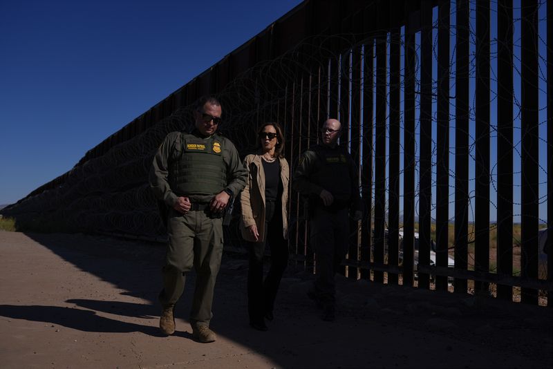 Gaya Kamala Harris Pakai Kalung Emas di Perbatasan Democratic presidential nominee Vice President Kamala Harris talks with John Modlin, the chief patrol agent for the Tucson Sector of the U.S. Border Patrol, right, and Blaine Bennett, the U.S. Border Patrol Douglas Station border patrol agent in charge, as she visits the U.S. border with Mexico in Douglas, Ariz., Friday, Sept. 27, 2024. (AP Photo/Carolyn Kaster)
