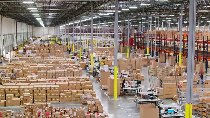 Drone shot of a busy fulfillment center in Southern California, where a large team of workers is picking items from shelves and packaging them for delivery.