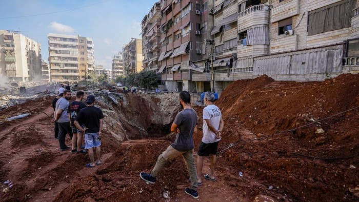 Israel Jatuhkan 80 Bom untuk Membunuh Pimpinan Hizbullah A woman reads the Quran at the site of the assassination of Hezbollah leader Hassan Nasrallah in Beirut's southern suburbs, Sunday, Sept. 29, 2024. (AP Photo/Hassan Ammar)