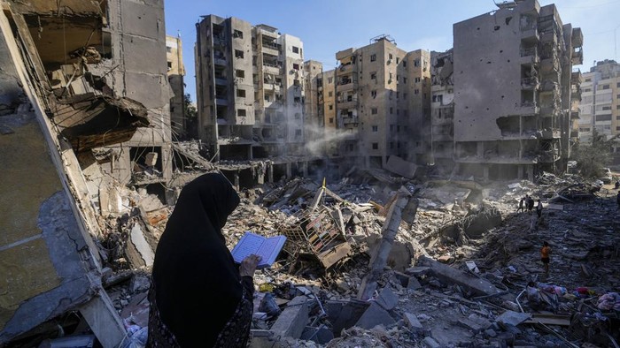 A woman reads the Quran at the site of the assassination of Hezbollah leader Hassan Nasrallah in Beirut's southern suburbs, Sunday, Sept. 29, 2024. (AP Photo/Hassan Ammar)