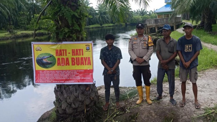Polisi memasang baliho imbauan di lokasi korban diterkam buaya. (Dok Polres Rohil)