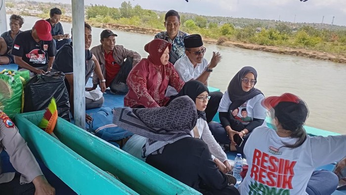Cagub Jatim Tri Rismaharini menumpangi perahu saat meninjau titik banjir di Sampang.
