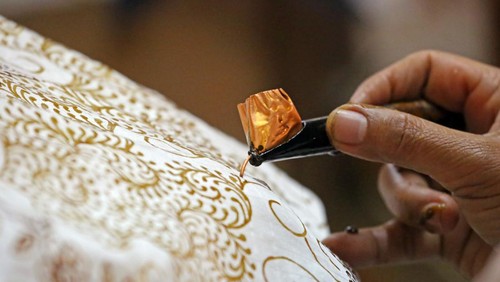 A woman uses a canting to apply wax to a cloth to make a pattern on a batik. Batik is a traditional form of decorating cloth, and Java is particularly famous for its variety of patterns and the quality of workmanship. The technique includes the manual application of wax between each dye bath to add each layer of colour individually.