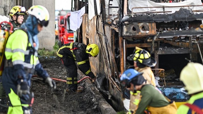 A firefighter sprays water on a burnt-out bus that was carrying students and teachers on the outskirts of Bangkok. Photo: AFP
