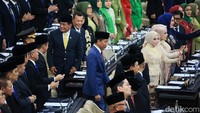 Jokowi hadir dengan mengenakan pakaian setelan jas lengkap dengan peci hitam.  
