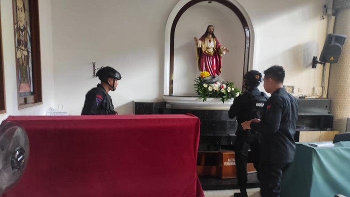 Tim Gegana penjinak bom menyisir Gereja Kristus Raja Surabaya usai temuan granat nanas di taman seberang gereja.
