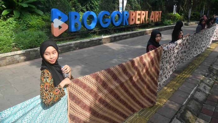 Sejumlah peserta membentangkan kain batik di pedestrian Kebun Raya Bogor, Jawa Barat, Rabu (2/10/2024). Kegiatan dalam rangka Hari Batik Nasional tersebut berhasil memecahkan rekor Original Rekor Indonesia (ORI) atas pembentangan kain batik motif Bogor dan motif Nusantara sepanjang 4,1 kilometer di pedestrian Kebun Raya Bogor. ANTARA FOTO/Arif Firmansyah/nym.
