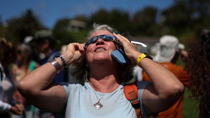 Antusias Warga Chile Amati Gerhana Matahari Cincin Api di Pulau Paskah A visitor wears special protective glasses to observe the upcoming solar eclipse at Hanga Piko archaeological monument area at Rapa Nui national park managed by the Mau Henua native community at Easter Island, Chile October 1, 2024. REUTERS/Ivan Alvarado