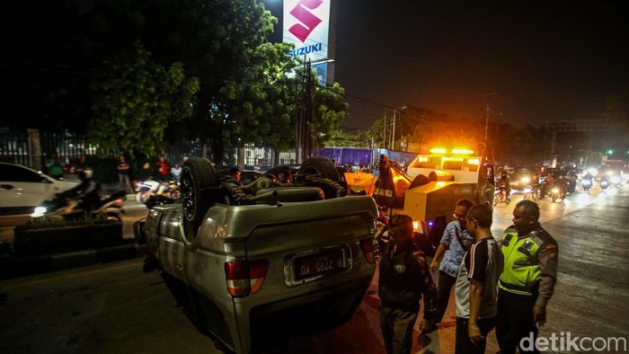 Mobil Plat Merah Terguling di Tambun Bekasi Sejumlah warga membantu petugas mengevakuasi mobil terbalik di Jalan Diponegoro, Tambun, Bekasi, Selasa (1/10/2024).