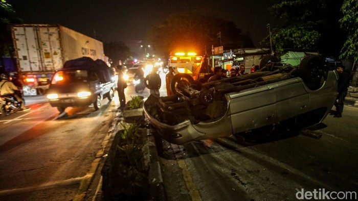 Sejumlah warga membantu petugas mengevakuasi mobil terbalik di Jalan Diponegoro, Tambun, Bekasi, Selasa (1/10/2024).