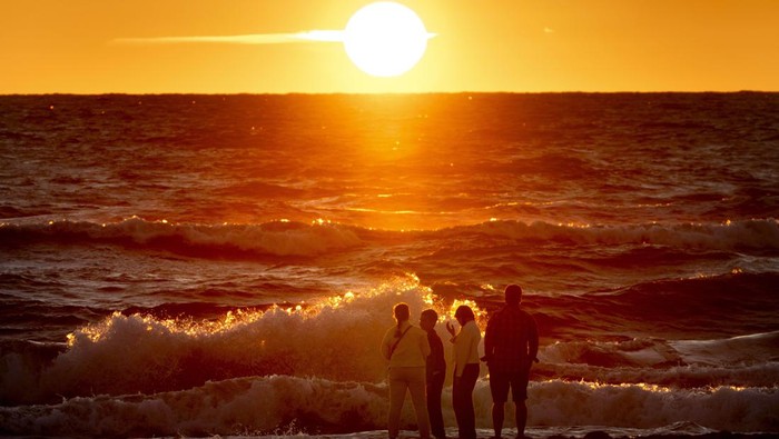 7 Destinasi dengan Pemandangan Senja Terindah di Dunia Russian holiday-makers watch the sunset at the seashore in Yantarny, on the Sambia Peninsula, about 40 kilometers (25 miles) from Kaliningrad, the western region of Russia, Monday, Aug. 12, 2024. (AP Photo/Alexander Zemlianichenko)