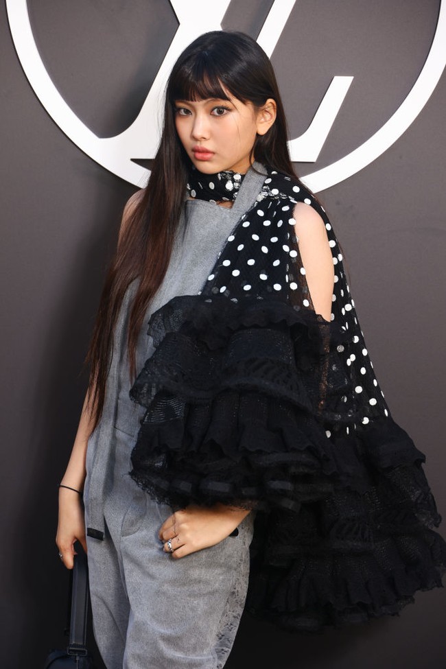 Personel grup KPop NewJeans itu tampil edgy memakai overall berwarna abu-abu dengan scarf hitam bermotif polkadot. Foto: Getty Images