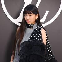 Personel grup KPop NewJeans itu tampil edgy memakai overall berwarna abu-abu dengan scarf hitam bermotif polkadot. Foto: Getty Images