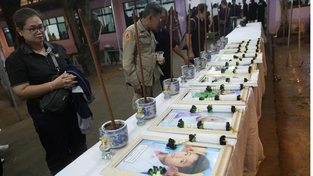 Relatives of victims in a bus fire carry portraits of the deceased in a procession at Wat Khao Phraya Sangkharam School Lan Sak , Uthai Thani province, Thailand, Thursday, Oct. 3, 2024. (AP Photo/Sakchai Lalit)