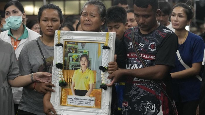 Momen Pilu Pemulangan Jenazah 23 Siswa-Guru yang Tewas dalam Kebakaran Bus Thailand Relatives of victims in a bus fire carry portraits of the deceased in a procession at Wat Khao Phraya Sangkharam School Lan Sak , Uthai Thani province, Thailand, Thursday, Oct. 3, 2024. (AP Photo/Sakchai Lalit)