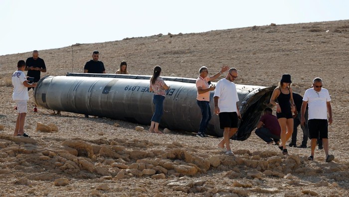 Penampakan Puing Rudal Balistik Iran Jadi Tontonan Warga Israel People walk around apparent remains of a ballistic missile lying in the desert, following an attack by Iran on Israel, near the southern city of Arad, Israel October 2, 2024. REUTERS/Amir Cohen