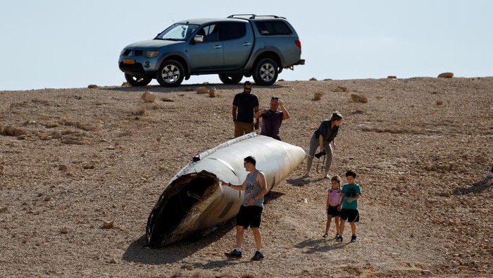 People walk around apparent remains of a ballistic missile lying in the desert, following an attack by Iran on Israel, near the southern city of Arad, Israel October 2, 2024. REUTERS/Amir Cohen