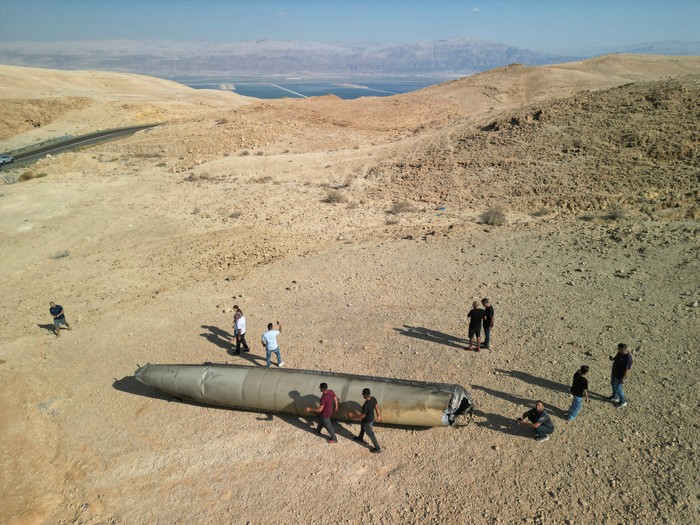 People walk around apparent remains of a ballistic missile lying in the desert, following an attack by Iran on Israel, near the southern city of Arad, Israel October 2, 2024. REUTERS/Amir Cohen