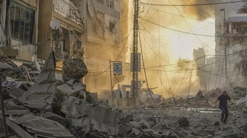 A man runs for cover as a smoke raises in the background following an Israeli airstrike in Dahiyeh, Beirut, Lebanon, Friday, Oct. 4, 2024. (AP Photo/Hassan Ammar)