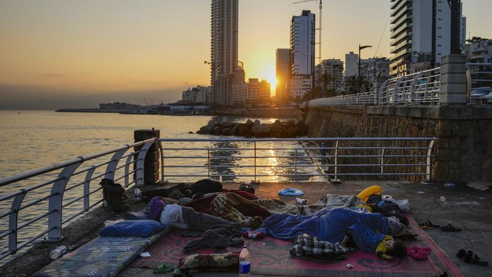 Families sleep on Beirut's corniche after fleeing the Israeli airstrikes in Beirut's southern suburb, Lebanon, Monday, Sept. 30, 2024. (AP Photo/Hassan Ammar)