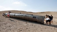 Orang-orang melihat sisa-sisa rudal balistik yang tergeletak di padang pasir, menyusul serangan Iran terhadap Israel, dekat kota selatan Arad, Israel. Perdana Menteri Israel Benjamin Netanyahu mengatakan bahwa Iran telah membuat kesalahan besar dan akan membayarnya.  REUTERS/Amir Cohen