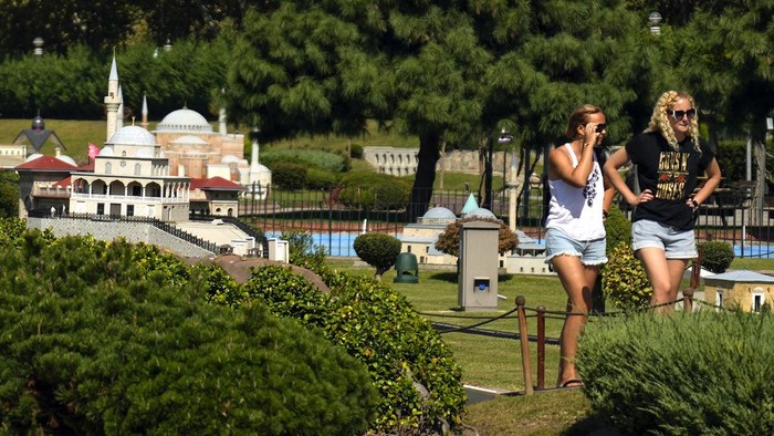 Tourists walk around miniature versions of Turkey's most famous landmarks and architectural structures, at the Miniaturk Museum, in Istanbul, Friday, Sept. 27, 2024. (AP Photo/Khalil Hamra)