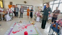 President and Chief Investment Officer of Alphabet and Google, Ruth Porat bersama guru dan murid mencoba permain edukasi di dalam kelas yang dibuat menggunakan Gemini.