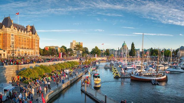 Canada Day in Victoria, Vancouver Island, Canada. Masses of people visiting the celebrations at inner harbour with the parliament building during sunset.