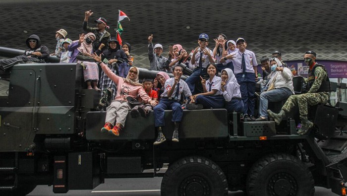 Potret Warga Ikut Naik Tank Saat Pawai Alutsista Melintas di Bundaran HI Pawai alutsista hari ini digelar dalam rangka memperingati HUT ke-79 TNI. Warga tampak berfoto di atas tank TNI saat pawai itu berlangsung.