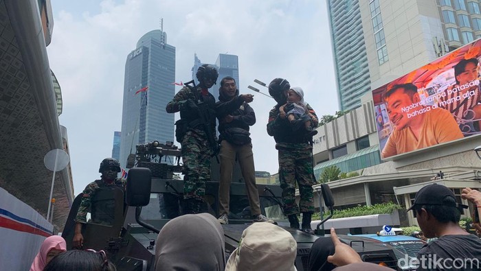Prajurit tampak melayani permintaan warga. Sejumlah warga naik ke atas tank dan berfoto dengan prajurit sebelum pawai kembali berjalan (Mulia/detikcom)