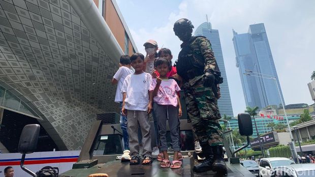 Prajurit tampak melayani permintaan warga. Sejumlah warga naik ke atas tank dan berfoto dengan prajurit sebelum pawai kembali berjalan (Mulia/detikcom)