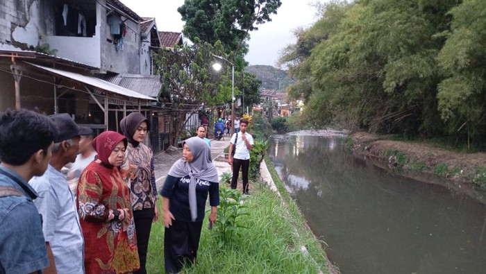 Cagub Tri Rismaharini memikirkan solusi untuk mengatasi banjir manakala hujan deras di sungai di Kampung Bandulan Gang 1, Kecamatan Sukun, Kota Malang