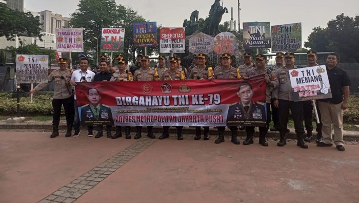 Jajaran Polres Metro Jakpus berjajar sambil membawa spanduk dan papan ucapan HUT ke-79 TNI di Patung Kuda