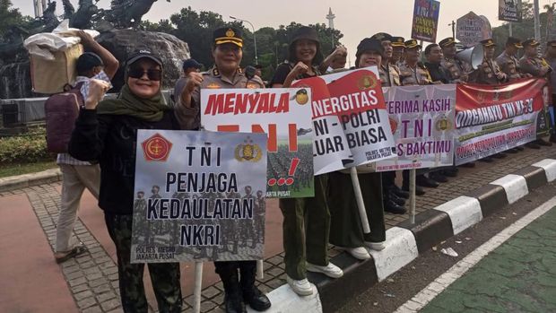 Jajaran Polres Metro Jakpus berjajar sambil membawa spanduk dan papan ucapan HUT ke-79 TNI di Patung Kuda