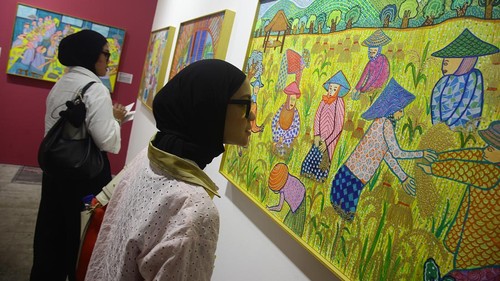 Pengunjung menikmati lukisan 'The Harvest' tentang ibu-ibu petani di sawah, karya pelukis autistik Oliver Wihardja yang dipamerkan di ajang Jakarta Art di JIEXPO Kemayoran, 4-6 Oktober 2024
