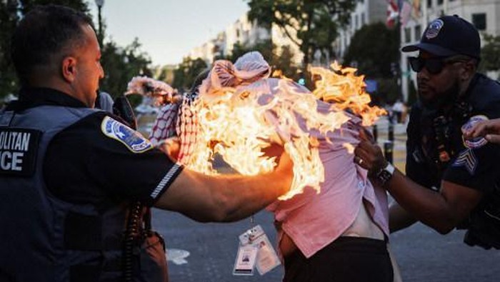 Police help a man who tried to set himself on fire as people demonstrate to mark one year of the war between Hamas and Israel near the White House in Washington, DC, on October 5, 2024. (Photo by Ting Shen / AFP)