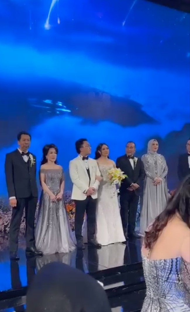 Di acara resepsinya Thalia dan Kenneth memilih tampil dengan busana pengantin internasional. Thalia tampil cantik dengan gaun pengantin berwarna putih, sementara suaminya mengenakan setelan tuksedo berwarna putih dipadukan dengan celana hitam dan dasi kupu-kupu. Foto: Instagram/@elmatheana