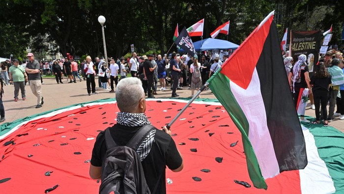 A drone view shows a giant Palestinian flag, as people march through the streets of the township of Lenasia, during the 