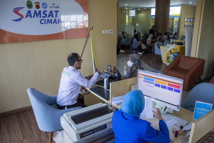 Petugas melayani warga yang membayar pajak kendaraan bermotor di bagian Samsat Cimahi Mal Pelayanan Publik (MPP), Cimahi, Jawa Barat, Senin (7/10/2024). Pemerintah Daerah Provinsi Jawa Barat mengadakan program pemutihan pajak kendaraan bermotor berupa bebas bea balik nama kepemilikan kendaraan bekas (BBNKB II), bebas denda pajak kendaraan bermotor, diskon pajak kendaraan bermotor,  bebas denda SWDKLLJ untuk tahun yang lewat serta bebas tunggakan pokok selama periode pembayaran 1 Oktober hingga 30 November 2024. ANTARA FOTO/Abdan Syakura/NA/nym.