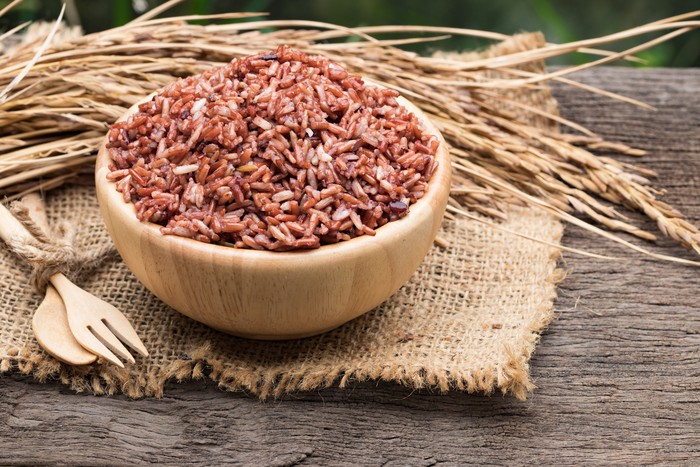 Brown rice in wooden bowl on gunny bag background