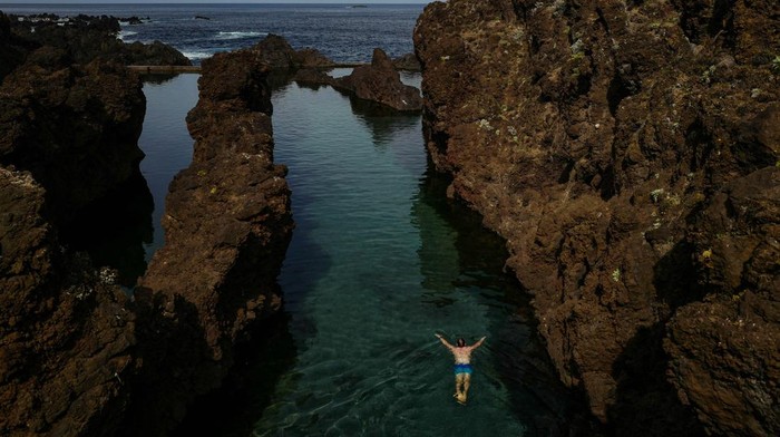 Menyelami Keindahan Kolam Renang Alami Porto Moniz di Portugal People enjoy a natural swimming pool in Porto Moniz on the Portuguese island of Madeira, Portugal, October 6, 2024. REUTERS/Pedro Nunes