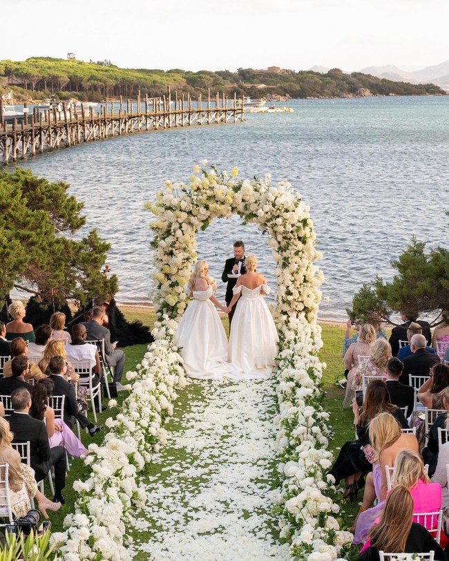 Dalam foto yang diunggah fotografer, kedua terlihat menikah selagi menikmati suasana lautan. Mereka pun kompak mengenakan ballgown putih berpotongan sabrina tapi detail dan potongan yang sedikit berbeda. Ramona mengaku bahwa mereka tidak sengaja memilih demikian tapi karena memang punya selera serupa. Foto: Instagram @rossini_photography
