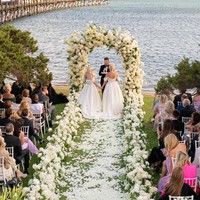 Dalam foto yang diunggah fotografer, kedua terlihat menikah selagi menikmati suasana lautan. Mereka pun kompak mengenakan ballgown putih berpotongan sabrina tapi detail dan potongan yang sedikit berbeda. Ramona mengaku bahwa mereka tidak sengaja memilih demikian tapi karena memang punya selera serupa. Foto: Instagram @rossini_photography