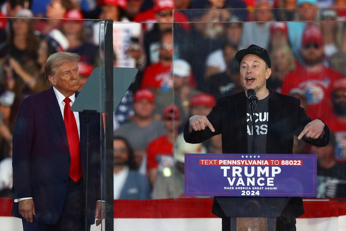 Tesla CEO and X owner Elon Musk speaks as Republican presidential nominee and former U.S. president Donald Trump looks on during a rally at the site of the July assassination attempt against Trump, in Butler, Pennsylvania, U.S., October 5, 2024. REUTERS/Carlos Barria     TPX IMAGES OF THE DAY