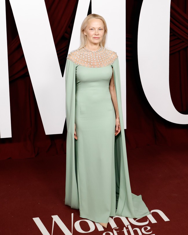 Meski makeup minimalis, Pamela Anderson tetap terlihat memesona dengan gaun hijau telur asin yang memiliki detail cape dengan panjang menyapu lantai. Bagian bahu dari gaun Pamela dibuat transparan dengan detail untaian mutiara perak. Foto: FilmMagic/Taylor Hill