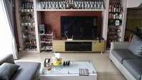 Di belakang ruang tamu, ada ruang keluarga untuk duduk dan menonton TV. Ruangan in berisi sofa set warna abu-abu serta rak built-in untuk memajang koleksi tumblr dan gelas dari manca negara. Foto: Pradita Utama
