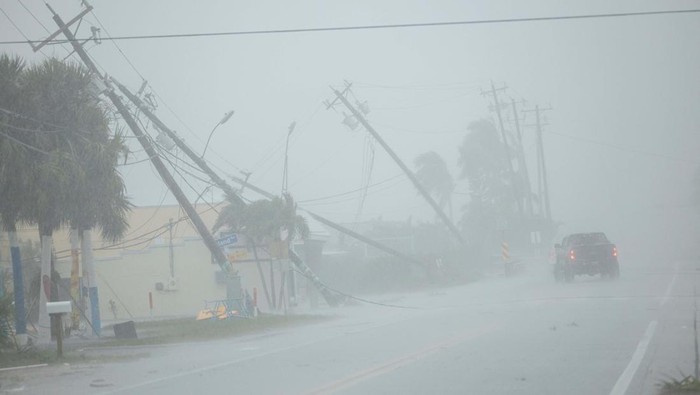 Badai Hilton Bikin Tiang Listrik Patah dan SPBU Rusak Parts of the roof of a gas station lie around palm trees after a passing tornado affected the area as Hurricane Milton approaches Fort Myers, Florida, U.S. October 9, 2024. REUTERS/Ricardo Arduengo