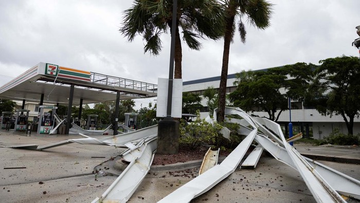 Badai Hilton Bikin Tiang Listrik Patah dan SPBU Rusak Parts of the roof of a gas station lie around palm trees after a passing tornado affected the area as Hurricane Milton approaches Fort Myers, Florida, U.S. October 9, 2024. REUTERS/Ricardo Arduengo