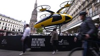 Pejalan kaki melewati prototype taksi terbang di pangkalan taksi di luar stasiun kereta Charing Cross di London, Rabu (9/10/2024).