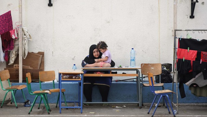 A woman talks with a child in a school turned into a temporary shelter for displaced people, during a visit by Hezbollah members of parliament, amid the ongoing hostilities between Hezbollah and Israel, in Beirut, Lebanon, October 9, 2024. REUTERS/Louisa Gouliamaki